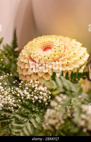 Un anguria scolpita in circondato da verde e fiori bianchi. Cibo decorato, a forma di disegno con molti dettagli. Tradizione tailandese Foto Stock