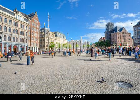 Turisti e locali raccogliere olandese a Piazza Dam, la piazza principale della città di Amsterdam su una mattina di sole a inizio autunno Foto Stock