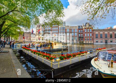 I turisti acquistano i biglietti presso uno stand per escursioni in barca su un canale nel centro storico di Amsterdam, Paesi Bassi Foto Stock