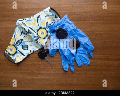 Maschera facciale in tessuto artigianale con motivo floreale giallo, blu e bianco con chiave per auto, portachiavi, guanti monouso e occhiali da sole. Fotografato con profondità bassa Foto Stock