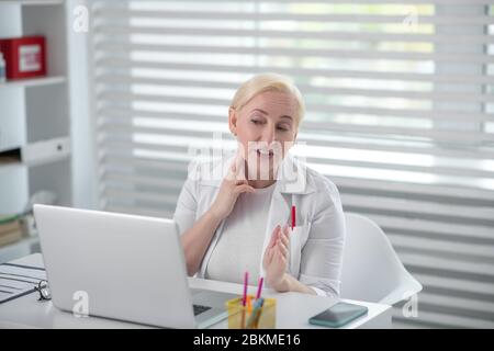 Donna bionda che ha una consultazione in linea su un laptop. Foto Stock