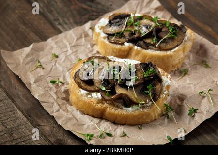 Bruschetta con formaggio, funghi e microgredi alla pergamena. Foto Stock