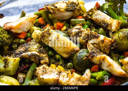 Pesce sano al forno con verdure, filetto di merluzzo fritto con lattuga e verdure da vicino, fuoco selettivo, spezie cavoli di bruxelles, vegetariano Foto Stock