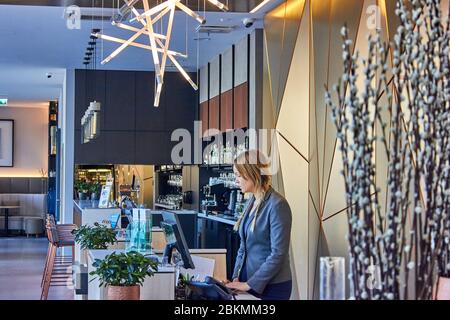 Giovane donna nella hall dell'hotel che aspetta gli ospiti Foto Stock