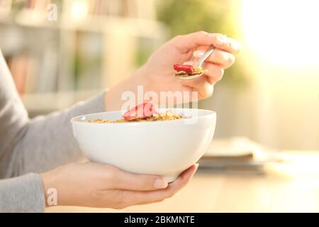 Primo piano delle mani della donna che tiene la ciotola di cereali con frutta pronta a mangiare colazione a casa Foto Stock