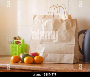 Sacchetti di carta, verdure fresche e frutta accanto a un telefono cellulare sul tavolo con utensili da cucina. Concetto di shopping, cibo sano e vegetariani Foto Stock