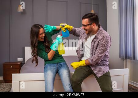 Giovane coppia felice si diverte durante la pulizia del loro appartamento. Foto Stock