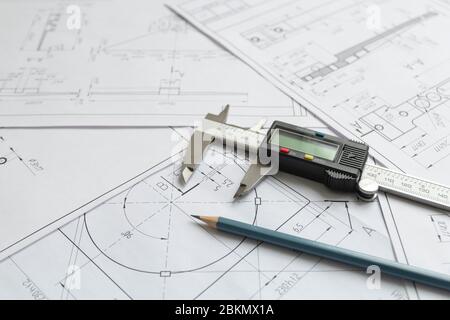 Vista dall'alto di uno strumento di misurazione calibro, matita e disegni di dettaglio.disegni tecnici, dettagli metallici. Foto Stock