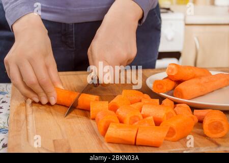 La donna in cucina taglia le carote a pezzi con un coltello Foto stock -  Alamy