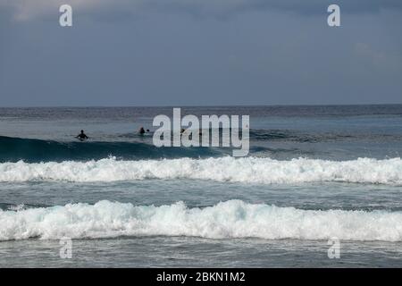 Uomo non identificato a bordo di surf in attesa di onda in blu acqua vista posteriore. I giovani attendono le onde. Surfista in attesa di un'onda. I surfisti aspettano t Foto Stock