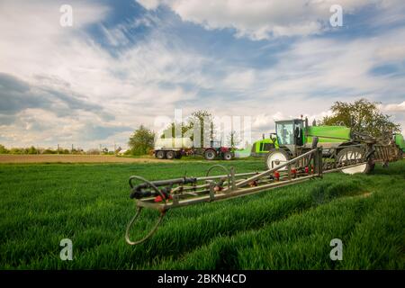 Trattore spruzzatura pesticidi, fertilizzazione sul campo vegetale con irroratore in primavera, concimazione Foto Stock