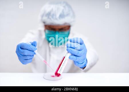 Il medico può indossare un guanto medico blu contenente la provetta con il test del sangue di Coronavirus Foto Stock