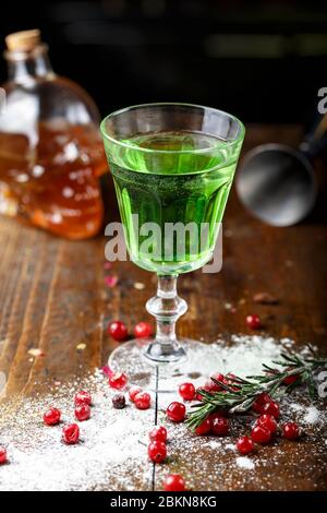 L'assenzio è versata in un bel vecchio vetro, sorge sul banco bar Sugar è splendidamente cosparso vicino al vetro e bacche rosse giacciono Foto Stock