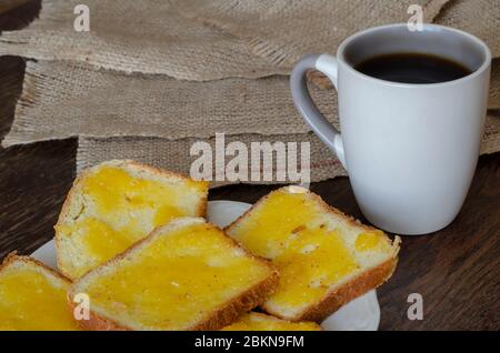 Fette di pane con miele di tiglio su fondo di legno scuro. Piatto con panini dolci. Una tazza di caffè sullo sfondo. Cibo fatto in casa. SID Foto Stock