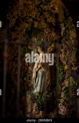 La statua della Madonna Maria che prega nella chiesa dei Gesuiti nella città vecchia di Dubrovnik, Dalmazia, Croazia. È circondata da rocce e vegetazione Foto Stock