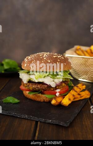 Scatto verticale di hamburger di lenticchie vegane fatto in casa su uno sfondo rustico scuro Foto Stock