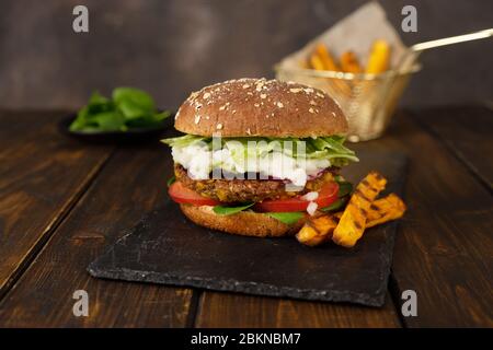 Delizioso hamburger di lenticchie vegane fresco fatto in casa su uno sfondo rustico scuro Foto Stock