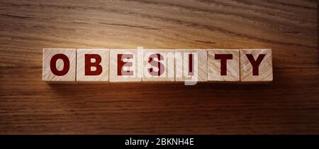 Parola di obesità scritta su blocco di legno su tavolo di legno.. Sano abitudini alimentari concetto Foto Stock