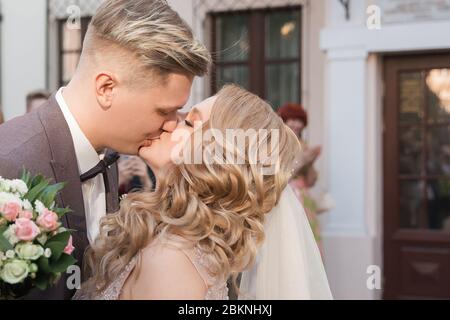 primo piano: buona sposa e sposo baciarsi sulla strada della città Foto Stock