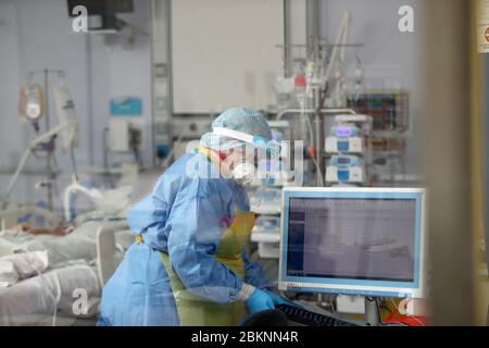 Nota per gli ed: Il viso del paziente è stato oscurato dal PA Picture Desk su richiesta dell'ospedale. Un membro del team di terapia intensiva tratta i pazienti di Covid-19 presso il Craigavon Area Hospital di Co Armagh, Irlanda del Nord. Foto Stock