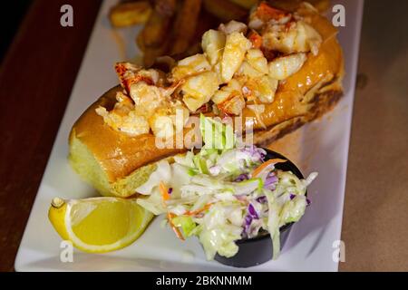 Rotolo di aragosta servito con patatine fritte, un cuneo di limone e coleslaw a Barrington, Nuova Scozia, Canada. L'aragosta è una prelibatezza locale nella C Foto Stock