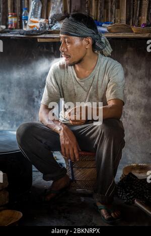 Uomo indiano che fuma. Prendendosi una pausa dalla cucina al Festival Hornbill, Nagaland, India Foto Stock