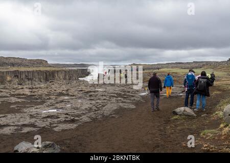 I visitatori camminano verso la cascata Selfoss nella rivolta del canyon Jökulsárgljúfur dalla più famosa cascata di Dettifoss, l'Islanda settentrionale. Foto Stock