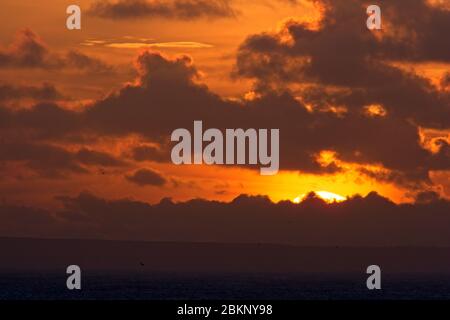 Nuvola e un'alba color arancio dorato sopra il Lizard, Cornovaglia, Inghilterra, Regno Unito. Foto Stock