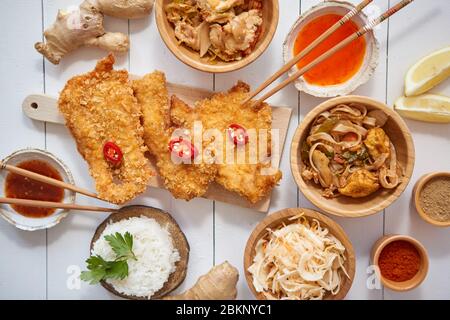 Pollo croccante fritto in pangrattato servito su un tavolo di legno bianco con insalata, spezie Foto Stock