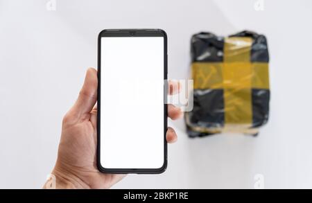 telefono cellulare con supporto a mano e pacchetto su sfondo bianco. Foto Stock
