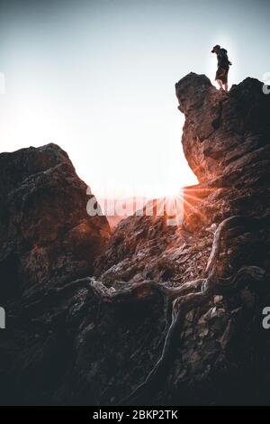 L uomo sulla cima della montagna e guardare il tramonto Foto Stock