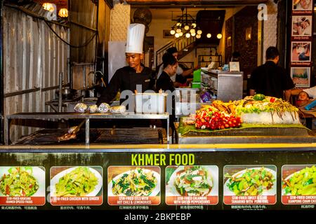 Uno chef cucina cibo presso UN ristorante nel mercato notturno, Siem Reap, Siem Reap Provincia, Cambogia. Foto Stock