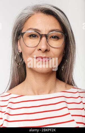 Immagine di donna matura adulto con lunghi capelli grigi che indossano occhiali guardando la fotocamera isolato su sfondo bianco Foto Stock