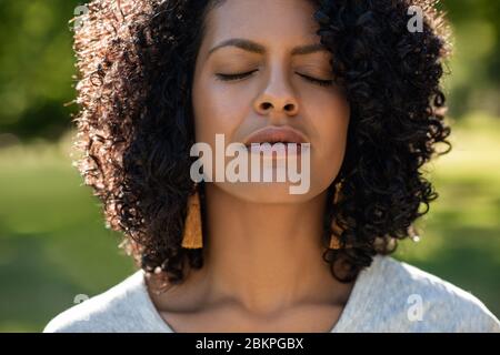 Giovane donna in piedi in un parco con gli occhi chiusi Foto Stock
