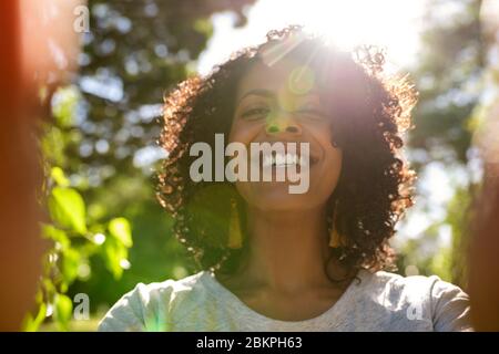 Donna ridente che prende un selfie fuori in una giornata di sole Foto Stock