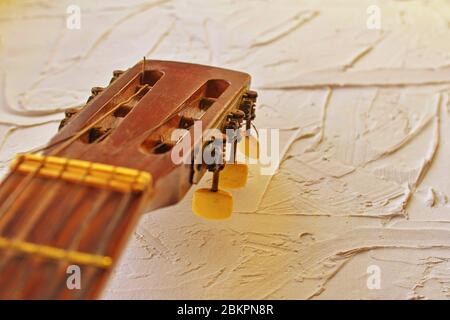 Vecchia testa di chitarra acustica con picchetti di sintonizzazione. Spazio di copia. Colori caldi e vivaci. Foto Stock