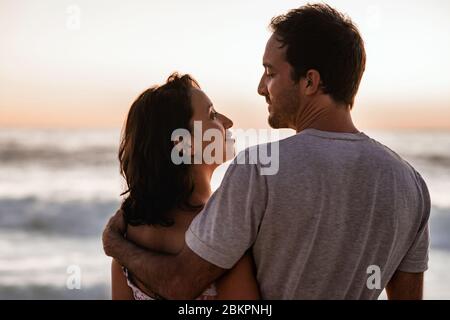 Una giovane coppia che ama guardare un tramonto sull'oceano Foto Stock