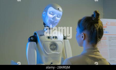 MOSCA, RUSSIA - 30 luglio 2018: Robostation - mostra del futuro. Robot divertente umanoide con display faccia parlare con la donna e cambiare volto a. Foto Stock