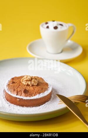 Gustose torte di pasticceria con noci e una tazza di caffè su sfondo giallo. Foto Stock