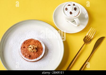 Gustose torte di pasticceria con noci e una tazza di caffè su sfondo giallo. Foto Stock
