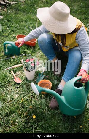 Donna giardiniera in cappello e guanti protettivi che scavano terreno con  rastrello nel suo giardino. Lavori di giardinaggio Foto stock - Alamy