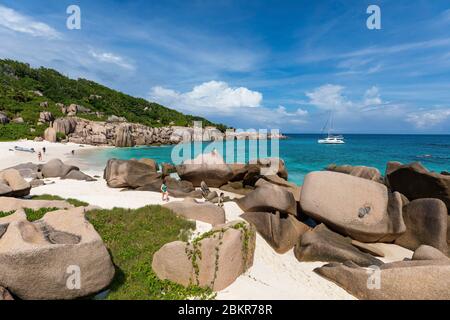 Seychelles, isola di Digue, Anse Marron, barca a vela Moorings 4800 all'ancora, rocce granite intorno alla spiaggia Foto Stock