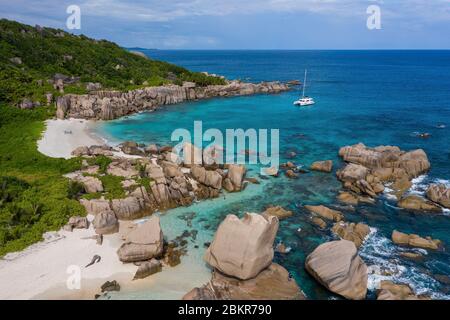 Seychelles, isola di Digue, Anse Marron, barca a vela Moorings 4800 all'ancora, spiaggia e rocce granite intorno (vista aerea) Foto Stock