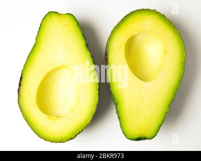 Due metà avocado con la pietra rimossa in senso opposto su uno sfondo bianco Foto Stock