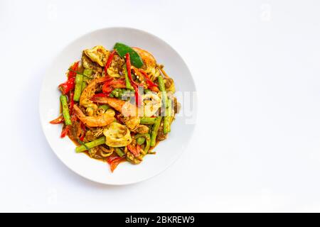 Piccante mescolare fritto shimp, calamari e maiale con pasta di peperoncino tailandese del sud e longbean su sfondo bianco. Foto Stock