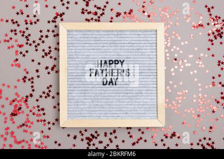 Letterboard con citazione Happy Favhers Day su sfondo grigio. Concetto di vacanza con confetti a stelle rosse. Foto Stock