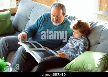 Caffè che beve. Nonno e suo nipote che trascorrono insieme il tempo isolato a casa. Divertirsi, leggere rivista, felice. Concetto di quarantena, famiglia, amore, realtà, insieme, educazione. Foto Stock