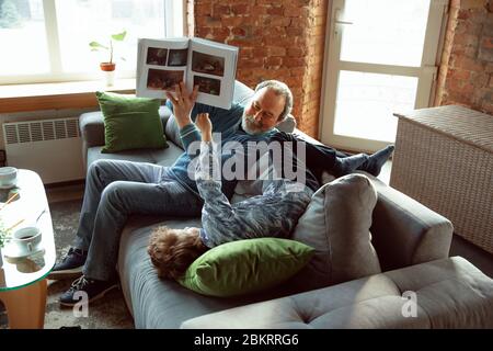 Caffè che beve. Nonno e suo nipote che trascorrono insieme il tempo isolato a casa. Divertirsi, leggere rivista, felice. Concetto di quarantena, famiglia, amore, realtà, insieme, educazione. Foto Stock