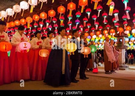 Corea del Sud, Provincia di Gyeongsang del Nord, Tempio di Jikjisa, donne che indossano hanbok, abiti tradizionali coreani e che pregano nel cortile illuminato da lanterna per il compleanno di Buddha Foto Stock