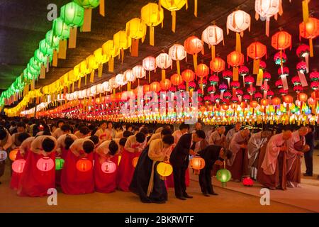 Corea del Sud, Provincia di Gyeongsang del Nord, Tempio di Jikjisa, donne che indossano hanbok, abiti tradizionali coreani e che si prosteggiano nel cortile illuminato da lanterna al compleanno di Buddha Foto Stock